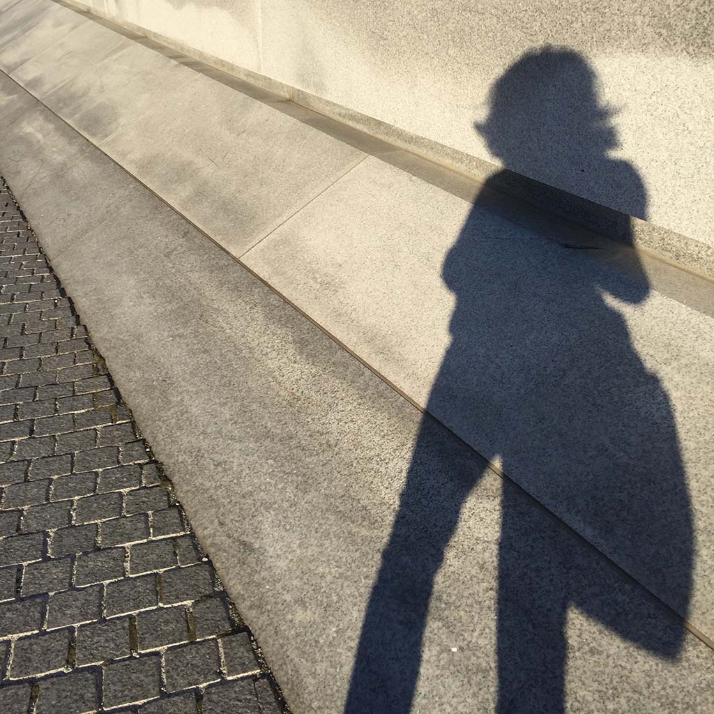 selfie of Victoria's shadow cast against the limestone grounds wall of a Gilded Age mansion in New York City.